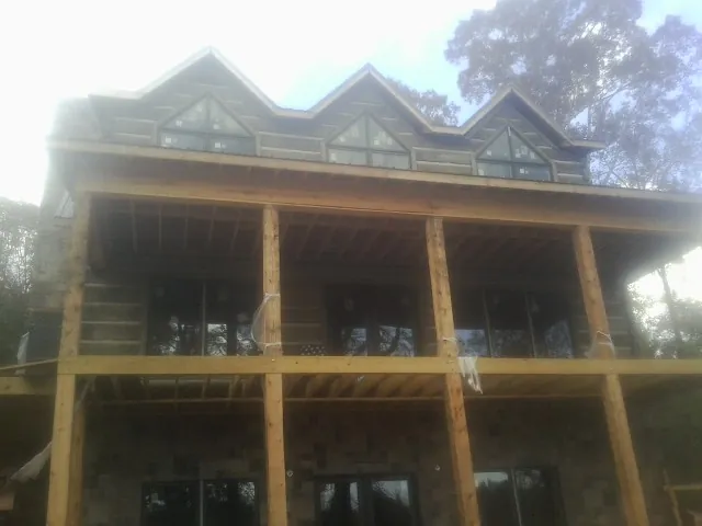Dormers and porch framing on a large log home under construction — Roof Coating work by our crew in Posen