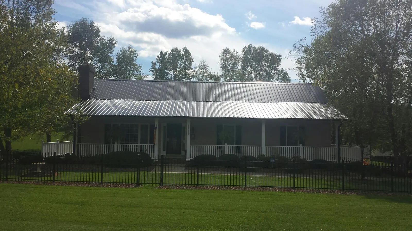 Gray metal roof on a brick ranch with a full width front porch — Gutter Guard Installation work by our crew in Posen