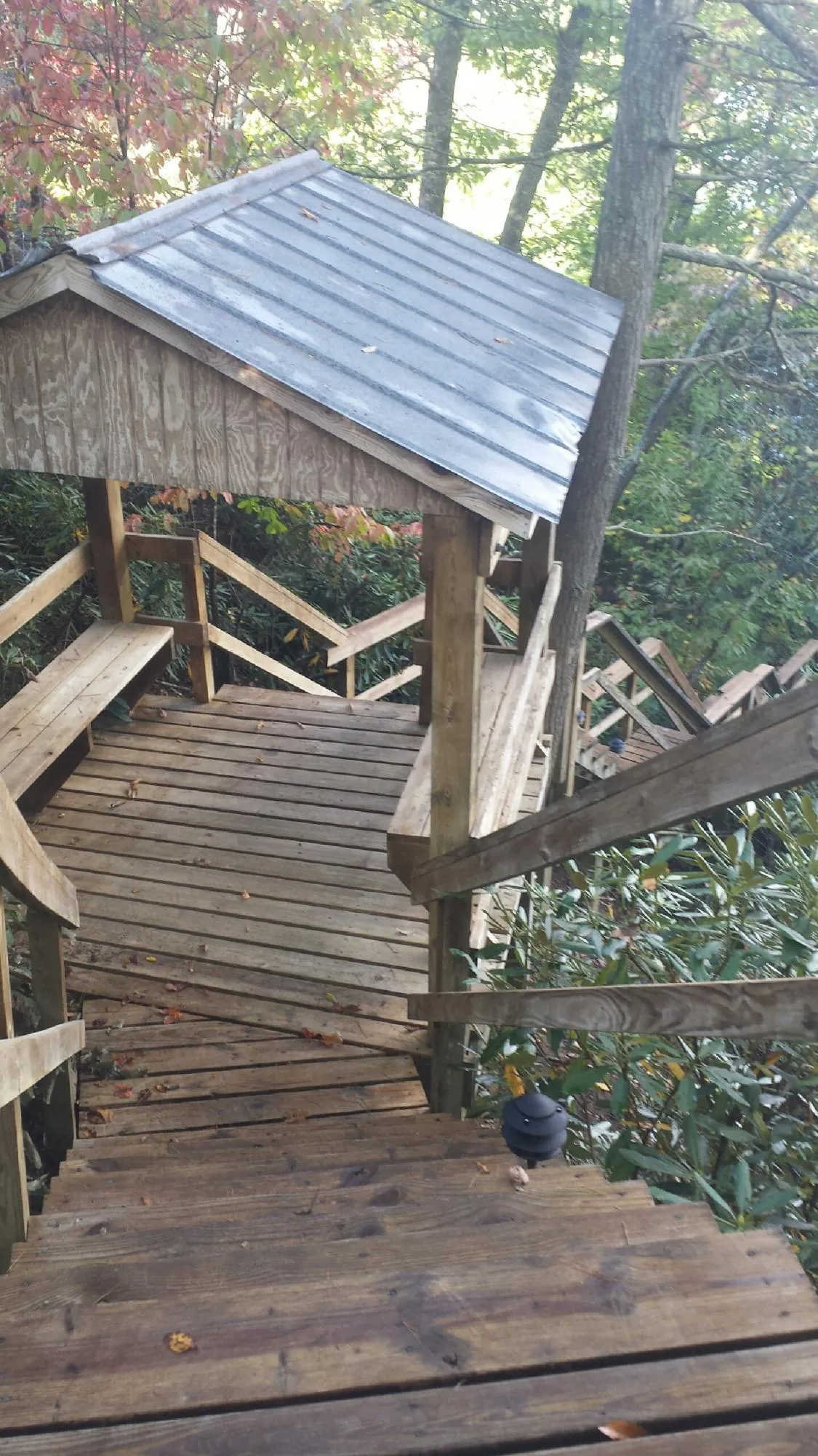 Metal roofed shelter over wooden steps on a wooded walkway — Skylight Repair & Installation work by our crew in Posen