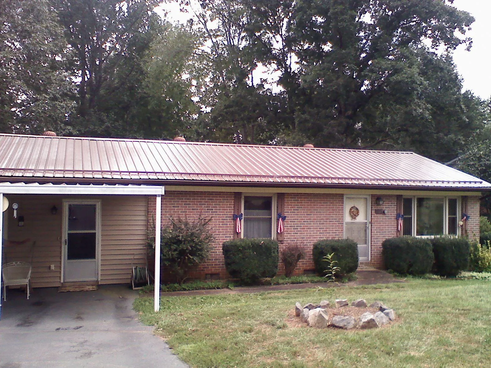 Bronze metal roof and carport on a brick ranch home — Roof Repair work by our crew in Posen