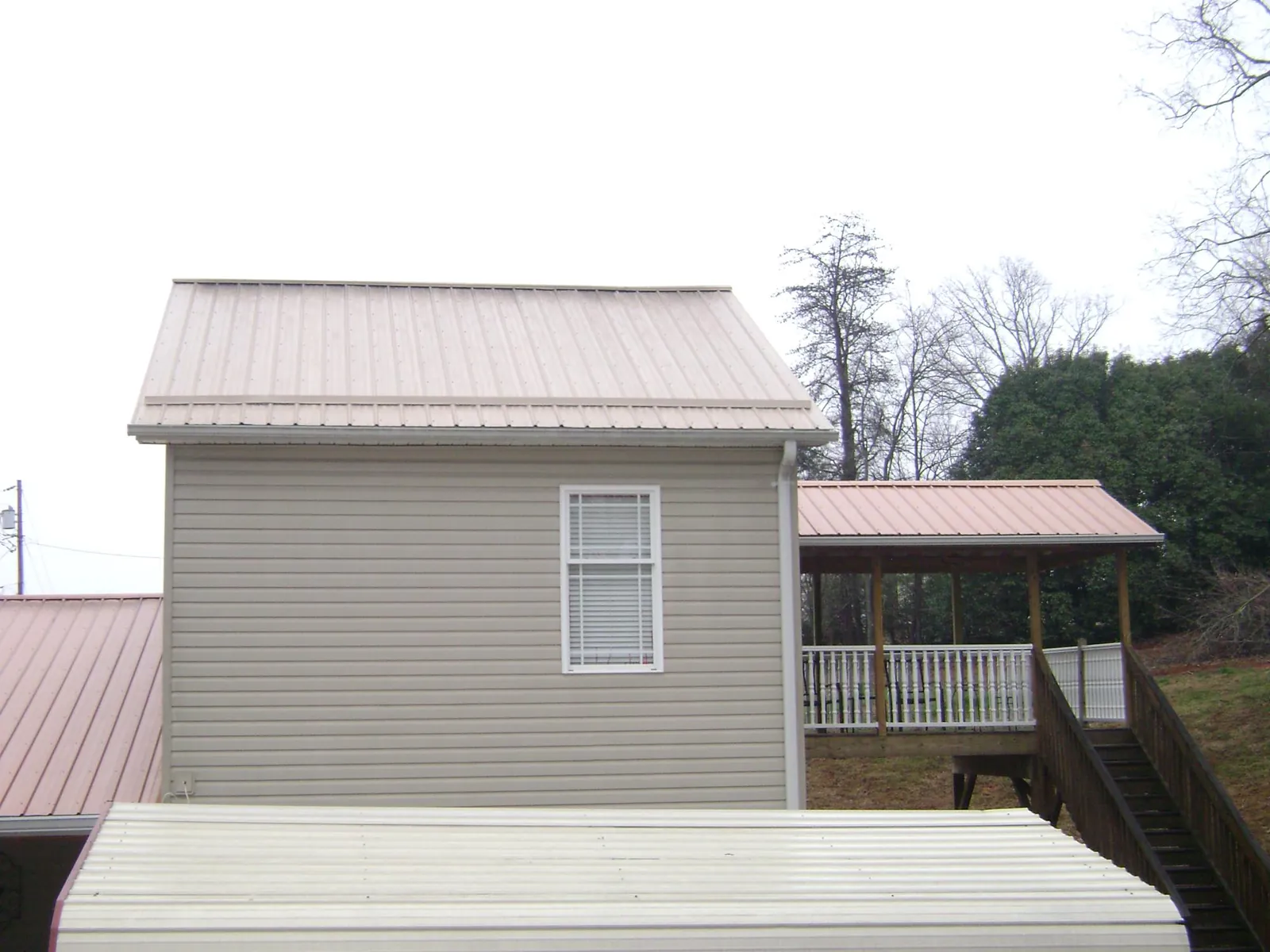 Tan metal roofs on a two story addition and attached porch, from a Roof Replacement job in Posen